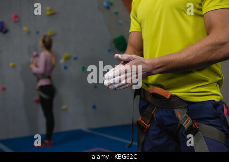 Sezione mediana di atleta maschio applicando polvere di gesso a mani nel club salute Foto Stock