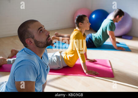 Elevato angolo di visione di un istruttore con gli studenti praticano cobra pongono in studio di yoga Foto Stock