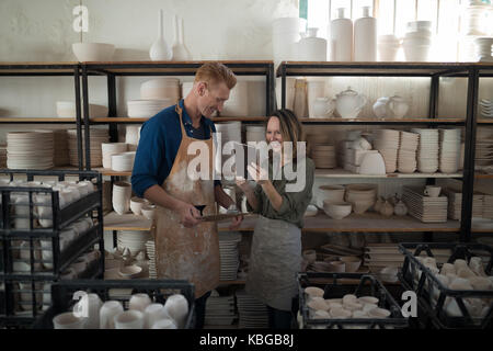 Maschio e femmina con potter digitale compressa nel laboratorio di ceramica Foto Stock