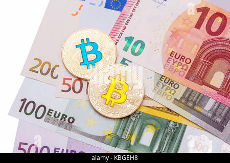 Il contante in euro su sfondo bianco coperto con due bitcoins. Foto Stock