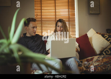 Paio utilizzando computer portatile sul divano di casa Foto Stock