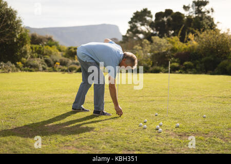 Senior uomo posizionando la pallina da golf nel campo da golf Foto Stock