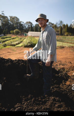 Agricoltore in piedi con le spade in campo in una giornata di sole Foto Stock