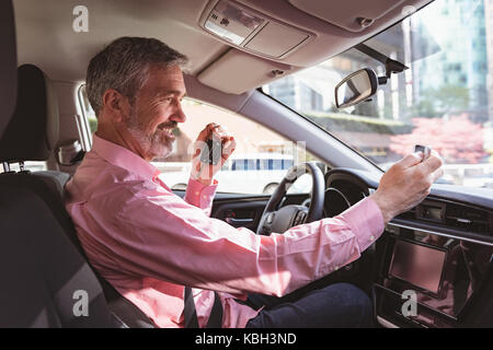 Felice l'uomo prendendo un selfie in auto Foto Stock