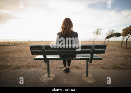 Vista posteriore di pensosa donna seduta sul banco di lavoro Foto Stock
