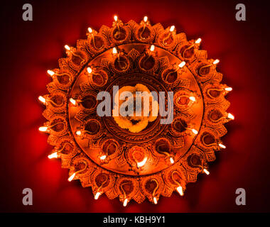 Foto di stock di un illuminato terra-cotta diwali lampada o diya con illustrazioni dettagliate su di esso. su un sfondo moody e messa a fuoco selettiva Foto Stock