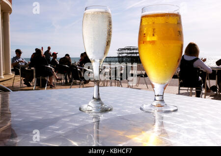 Bicchiere di Prosecco spumante e una birra moretti al caffè sul mare dal Molo Ovest di Brighton Foto Stock