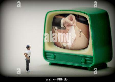 Figura in miniatura di un uomo di fronte a un televisore vedi la notizia delle elezioni spagnole, immagine concettuale Foto Stock