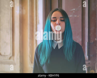 Carino il modello gotico soffia bubblegum. street punk o hipster donna studente con colorate blu capelli tinti, piercing,lenti,orecchie gallerie e insolito hairsty Foto Stock