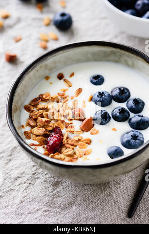 Yogurt con mirtilli e granola in una ciotola. Primo piano. Mangiare sano snack sano e la dieta fitness sport pasto Foto Stock