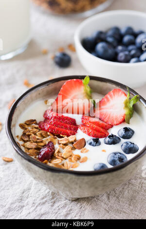 Yogurt con fragole, mirtilli e avena granola muesli in una ciotola. Primo piano Foto Stock