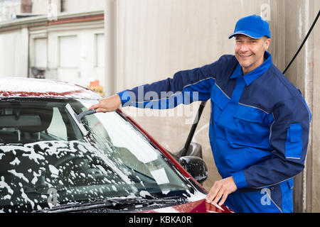 Immagine ritagliata del lavoratore manuale di lavaggio del parabrezza auto presso la stazione di servizio Foto Stock