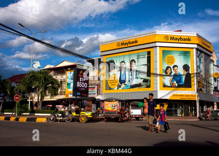 Tuk tuks sono parcheggiate su una strada di città di fronte a una succursale di maybank in Kampong Cham, Cambogia. Foto Stock