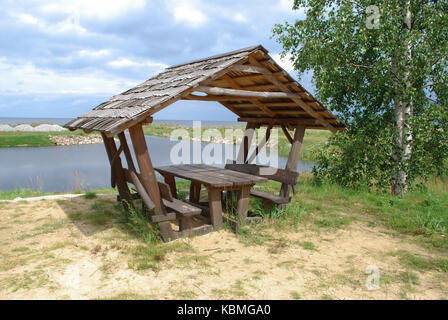 Attrezzata area pic-nic (panchine di legno e tettoia) sulla riva del lago. Foto Stock