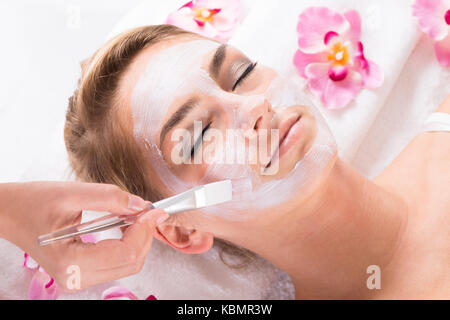 Immagine ritagliata di estetista applicato la maschera su clienti faccia a salon Foto Stock