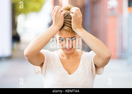 Triste giovane donna che soffre di mal di testa all'aperto Foto Stock