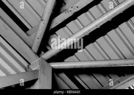 Fotografia formalista. Semplice fotografia in bianco e nero di metallo architettura industriale con uno squarcio di travature metalliche convergenti in basso a sinistra. Foto Stock