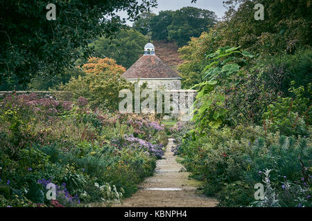 Un informale sentiero di ghiaia attraverso un grande giardino cottage con colombaia Foto Stock