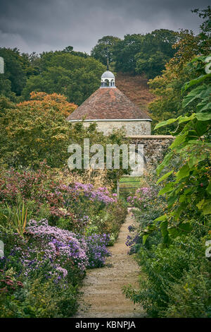 Un informale sentiero di ghiaia attraverso un grande giardino cottage con colombaia Foto Stock