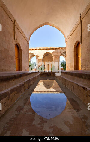 Antica scuola teologica conosciuta come Zinciriye Madrasah e riflessione nella sua piscina poco profonda nel suo cortile, a Mardin, Turchia. Foto Stock