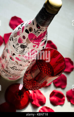 Cardiff Wales, Regno Unito. Xiii febbraio 2017. decorate bottiglia di lambrini si siede accanto a un rosso flute da champagne circondato da petali di rosa. © amy fa Foto Stock