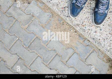 Sneakers blu sul blocco di calcestruzzo pavimentazione. vista dall'alto. Foto Stock