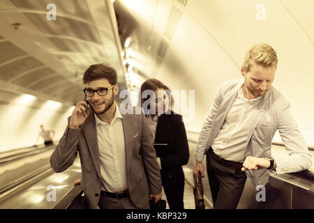 I suoi collaboratori utilizzando le scale della metropolitana insieme Foto Stock