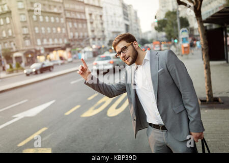 Imprenditore agitando per un taxi Foto Stock