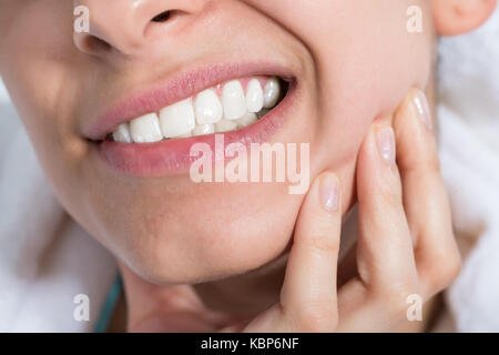 Primo piano della giovane donna che soffre di mal di denti a casa Foto Stock