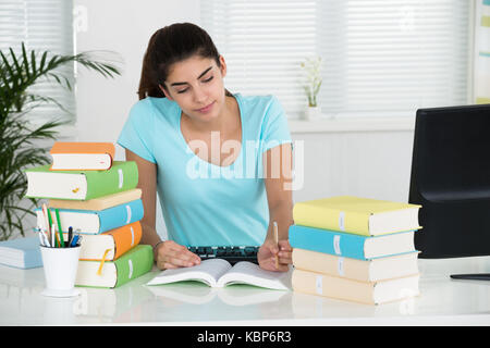 Giovane studentessa scrivendo note alla scrivania in ufficio in casa Foto Stock