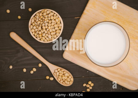 Vetro con latte di soia e semi di soia su sfondo di legno Foto Stock