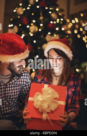 Ragazza cerca nella casella di apertura con il nuovo anno regalo da fidanzato Foto Stock