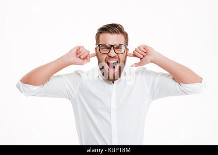 Irritato giovane uomo barbuto chiudendo il suo orecchio rimanendo isolate su sfondo bianco Foto Stock