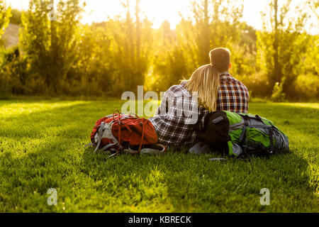 Coppia giovane con zaini seduto sull'erba Foto Stock