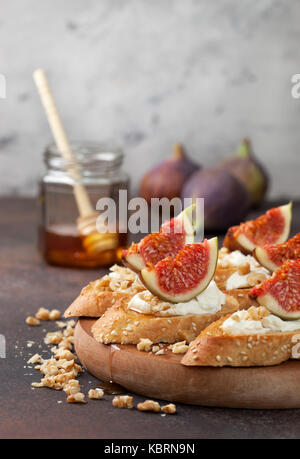 Panini con fichi, ricotta, miele e noci su uno sfondo marrone Foto Stock