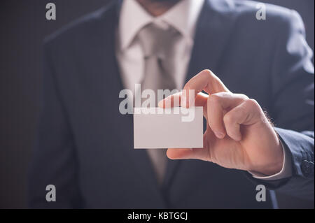 Man mano che mostra business card isolato su sfondo scuro Foto Stock