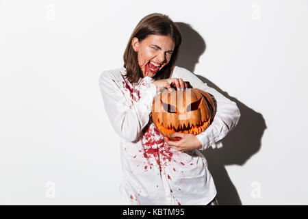 Mad scary zombie donna ricoperto di macchie di sangue in possesso di una zucca di Halloween isolate su sfondo bianco Foto Stock