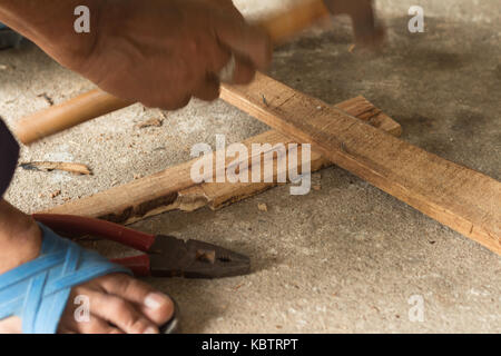 Il falegname è di colpire un chiodo per asse di legno(soft focus) Foto Stock