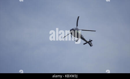 Elicottero nel cielo nuvoloso con un fulmine. elicottero da sotto volare attraverso il cielo nuvoloso. elicottero in bilico contro la giornata piena di sole e cielo molto nuvoloso Foto Stock