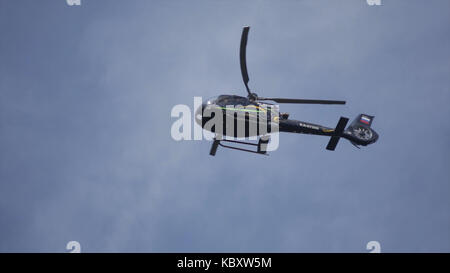 Elicottero nel cielo nuvoloso con un fulmine. elicottero da sotto volare attraverso il cielo nuvoloso. elicottero in bilico contro la giornata piena di sole e cielo molto nuvoloso Foto Stock