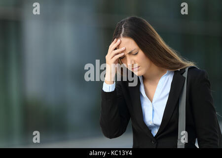 Single Executive sofferenza mal di testa a piedi al di fuori sulla strada Foto Stock