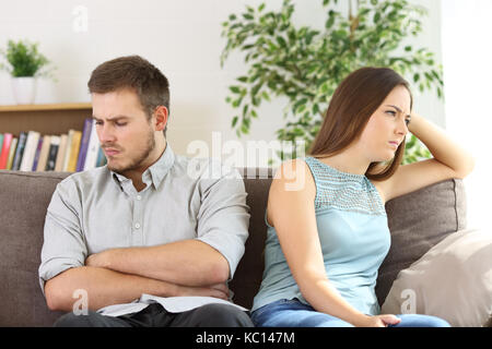 Arrabbiato giovane ignorando ogni altro argomento dopo la seduta su un divano a casa Foto Stock
