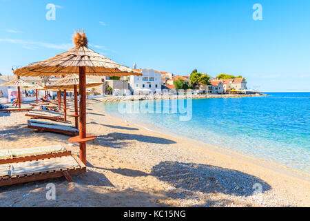 Città di Primosten, Croazia - 5 Sep, 2017: lettini con ombrelloni sulla spiaggia vuota nella città di Primosten, Dalmazia, Croazia. Foto Stock