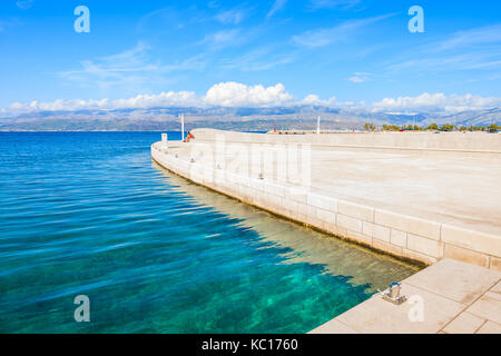 Il mare limpido e cristallino nel porto di Supetar con montagne sulla terraferma visibile in distanza, isola di Brac, Croazia Foto Stock