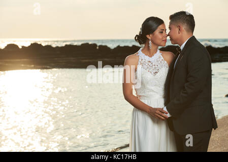 Lo sposo a baciare la sposa su ocean Sunset beach sfondo. matrimonio romantico in spiaggia tropicale Foto Stock