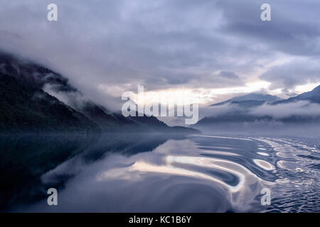 Lugubre mattina presto luce autunnale con nebbia, riflessioni e cloud inversione su ullswater preso dal glenridding howtown al sistema di cottura a vapore Foto Stock
