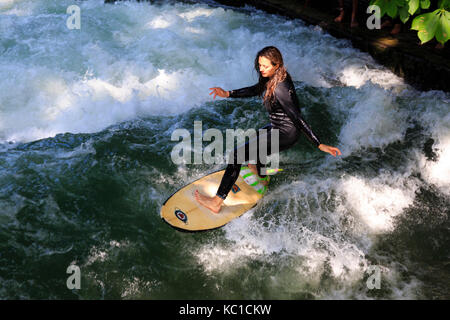 Surf femmina sul Eisbach fiume Isar surf, Englisher Garten Monaco di Baviera, Germania Foto Stock