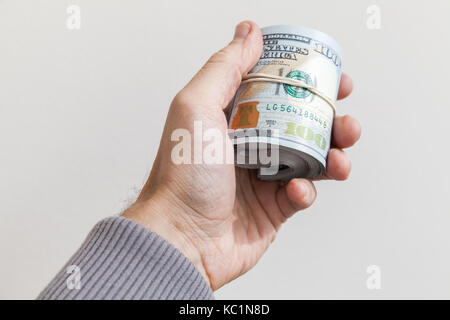 Rotolo di nuovo un centinaio di dollari note in mano maschio Foto Stock