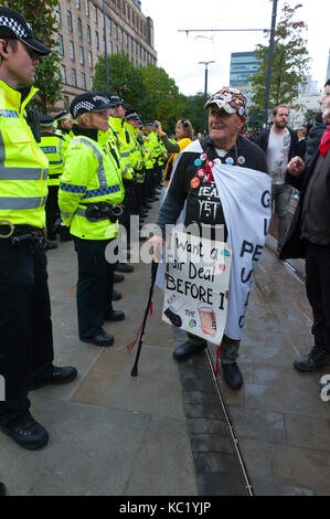 Manchester, Regno Unito. 1 Ottobre, 2017. Pensionato falegname & Joiner ottanta-tre-anno-vecchio Terry Hutt da Camden, Londra, passeggiate una linea di funzionari di polizia vicino al partito Tory Conference Center. Terry è un attivista per DAN - Direct Action network. Ant-Fracking attivisti e dusabled anti Tory attivisti soddisfare pesanti di sicurezza della polizia in piazza san Pietro nei pressi del centro conferenze. Pro-pace, anti-austerità, alle manifestazioni contro la guerra, comprese manifestazioni, incontri pubblici, commedia, musica e cultura, hanno luogo durante i quattro giorni del congresso del Partito Conservatore di Manchester, UK. 1° - 4° OTT 2017. La protes Foto Stock