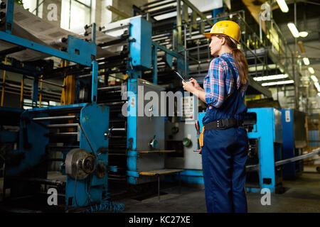Ritratto di donna operaio di fabbrica cercando di macchine da stampa in fabbrica moderna Foto Stock